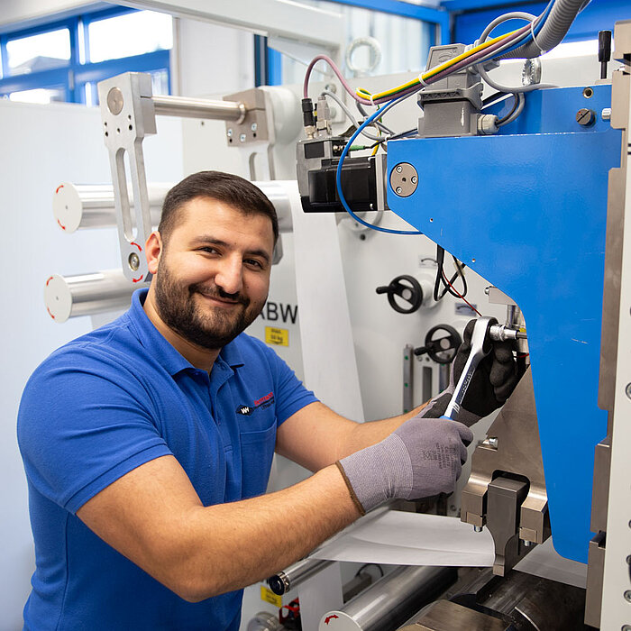 Herrmann Ultrasonics employee adjusts a welding machine with a ratchet
